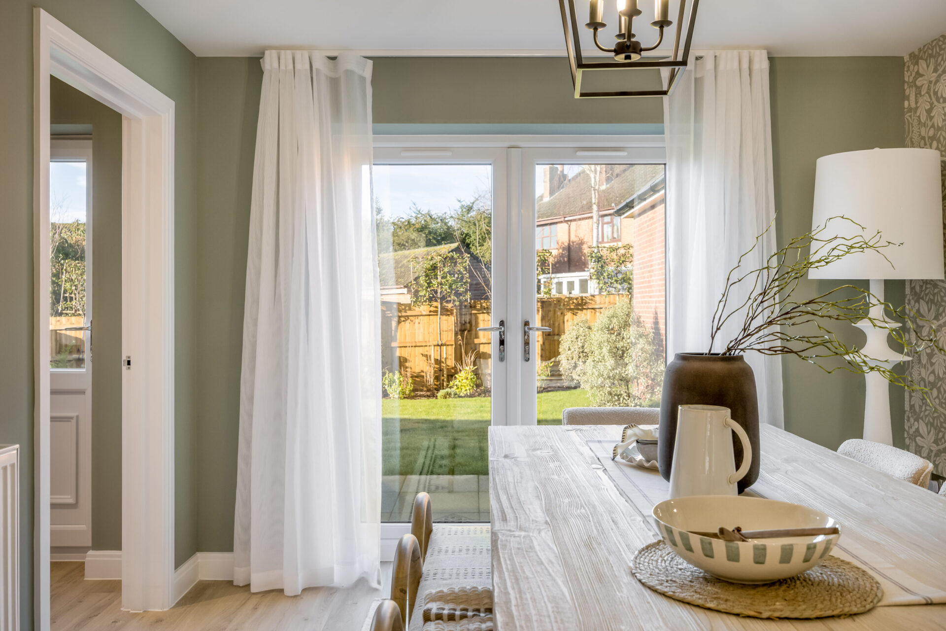 A view looking over a dining table out to the garden inside the Morden home by Wyatt Homes.